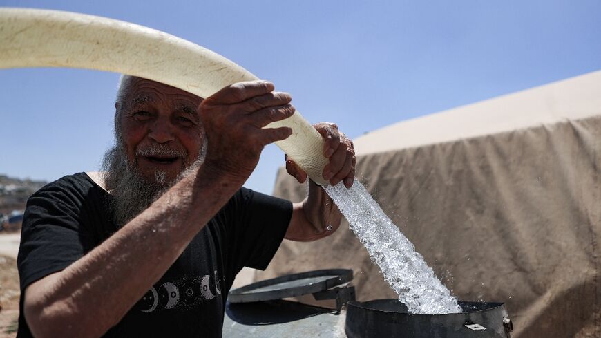 A man fills barrels with water at a camp for internally displaced people in northern Syria