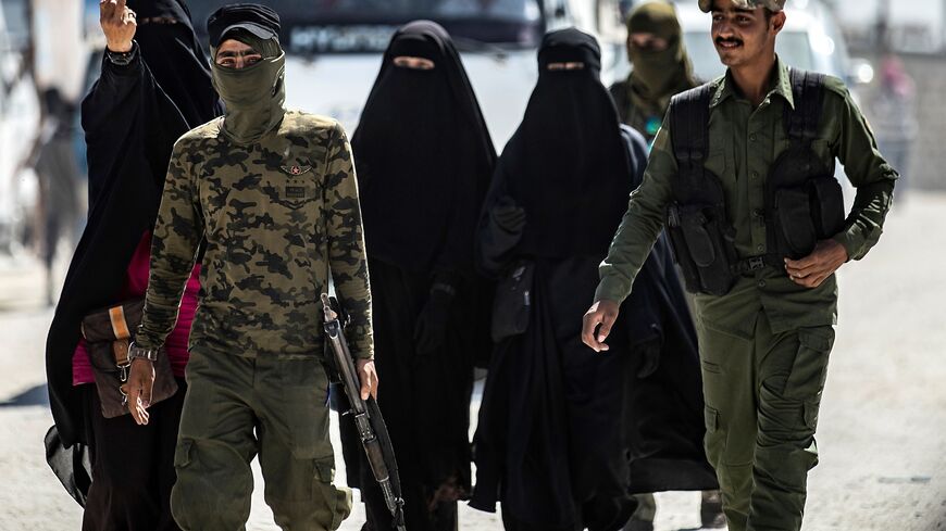 An internal security patrol escorts women, reportedly wives of Islamic State fighters, in the al-Hol camp in al-Hasakah governorate in northeastern Syria, on July 23, 2019. 