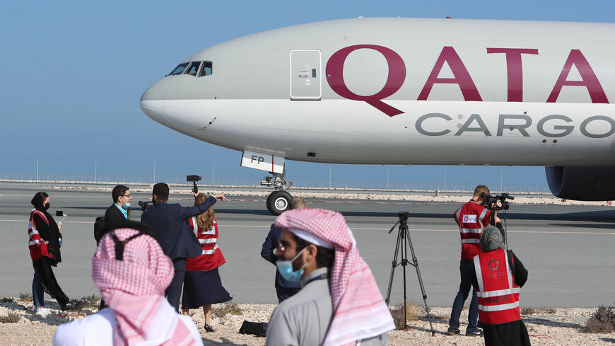 Reporters gather near a Qatar Airways cargo airplane on the tarmac of Hamad International Airport, as the first commercial flight to Saudi Arabia in three and a half years following a Gulf diplomatic thaw prepares for take-off, Doha, Qatar, Jan. 11, 2021. 