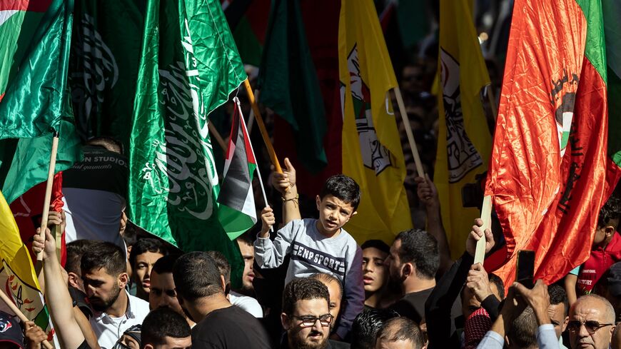 Palestinians lift flags of the Hamas and Fatah groups as they demonstrate in Ramallah in the occupied West Bank on November 10, 2023, amid ongoing battles between Israel and the Hamas movement in the Gaza Strip. 