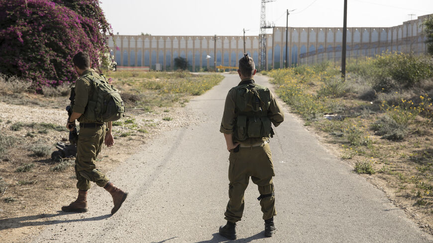 Israeli soldiers stand amid protective barriers near the border fence with the Gaza Strip in Netiv HaAsara, Israel, Nov. 17, 2023.