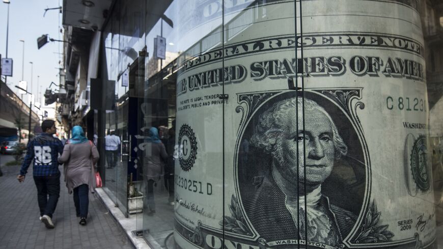 People walk past a currency exchange shop displaying a giant US dollars banknote in downtown Cairo on November 3, 2016. Egypt floated the country's pound as part of a raft of reforms, after a dollar crunch and exorbitant black market trade threatened to grind some imports to a halt. / AFP / KHALED DESOUKI (Photo credit should read KHALED DESOUKI/AFP via Getty Images)