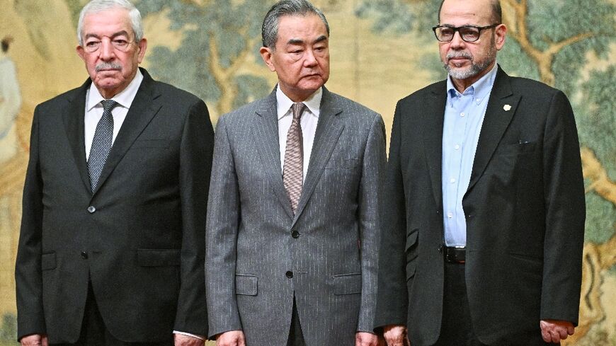 Chinese Foreign Minister Wang Yi stands between senior Hamas official Musa Abu Marzuk (R) and Fatah envoy Mahmud al-Aloul at the signing ceremony in Beijing