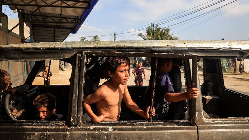 Displaced children play in a burned out vehicle in Deir al-Balah city, central Gaza 