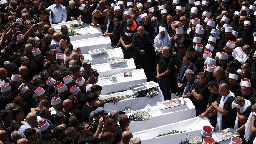 Druze elders and mourners surround the coffins of many of the 12 people killed in a rocket strike from Lebanon in the Israeli-annexed Golan Heights