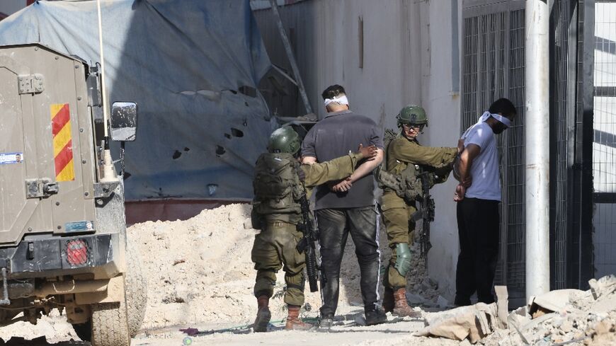 Israeli soldiers arrest Palestinians during a raid in the Nur Shams refugee camp in the occupied West Bank