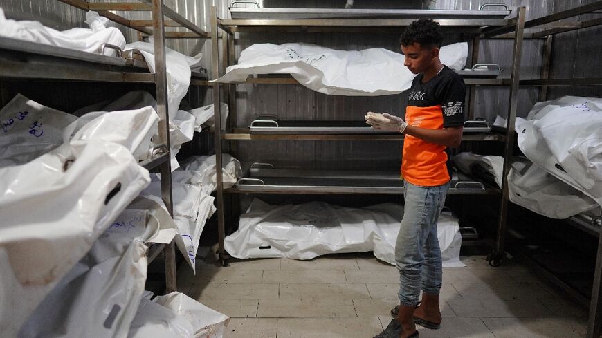 A young Palestinian who works with his father at the morgue at the Nasser Hospital in southern Gaza stands next to the bodies of people killed in the fighting who have yet to be identified