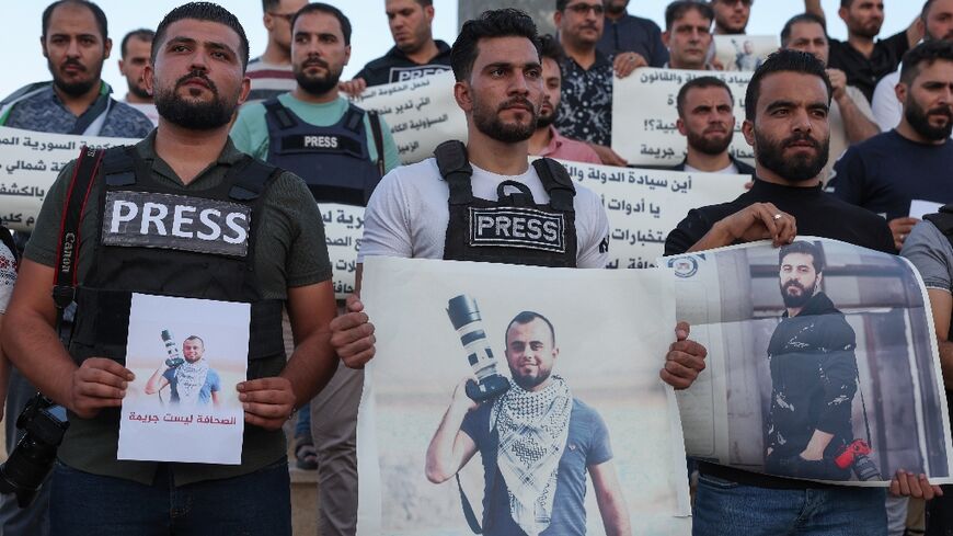 Syrian journalists lift placards protesting the detention of colleague Bakr al-Kassem