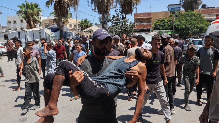 A Palestinian carries a man wounded in Israeli bombardment in Deir el-Balah