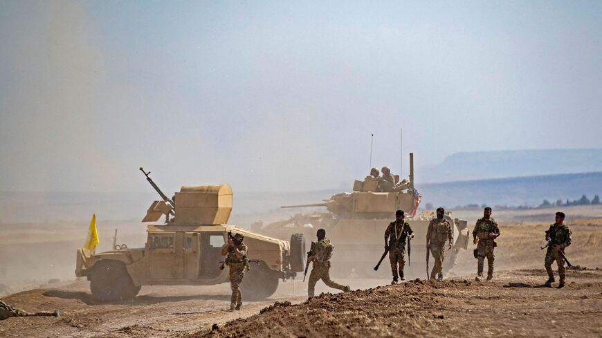 Fighters of the Syrian Democratic Forces (SDF) gather near a US Bradley Fighting Vehicle (BFV) during a joint military exercise with forces of the US-led "Combined Joint Task Force-Operation Inherent Resolve" coalition against the Islamic State (IS) group in the countryside of the town of al-Malikiya (Derik in Kurdish) in Syria's northeastern Hasakah province on Sept. 7, 2022. 