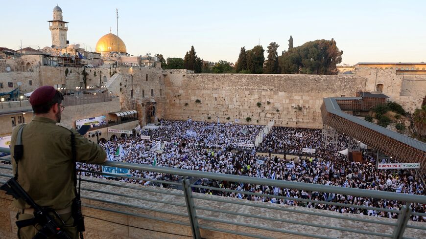 An armed Israeli soldier watches nationalists gathered at the Western Wall in the Old City of Jerusalem on June 5, 2024, during the so-called Jerusalem Day flag march.