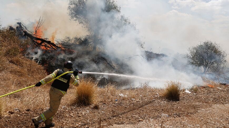 Firefighters douse flames in a field in Israel's north after a drone launched from southern Lebanon started a fire