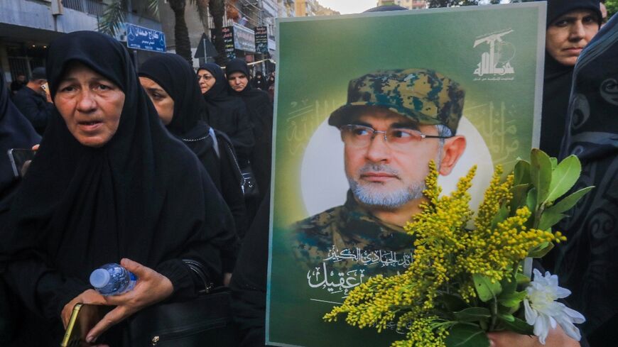 Black-clad mourners file past, one bearing a picture of killed Radwan Force chief Ibrahim Aqil