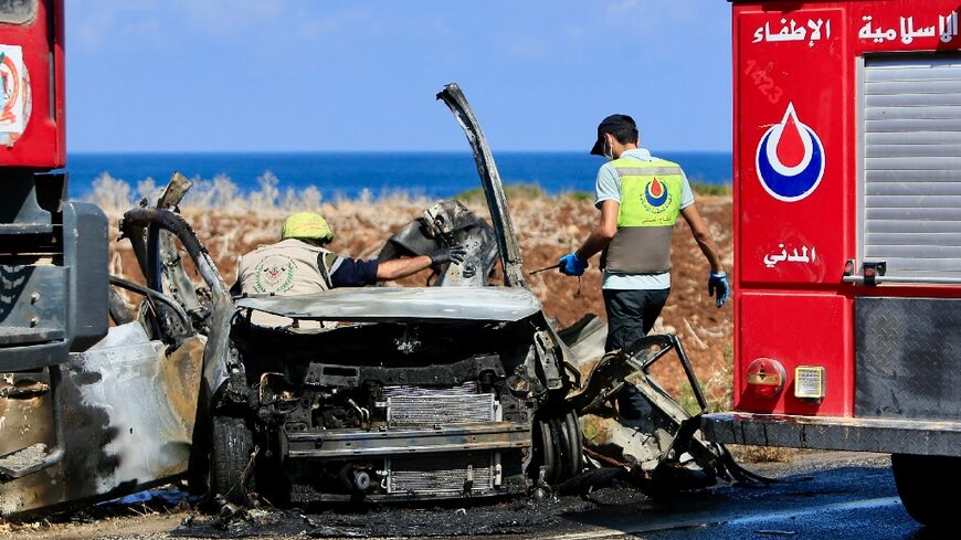 Civil Defence teams inspect a charred car that was reportedly hit by an Israeli drone strike on the road leading to the southern Lebanese coastal town of Naqura on the border with Israel