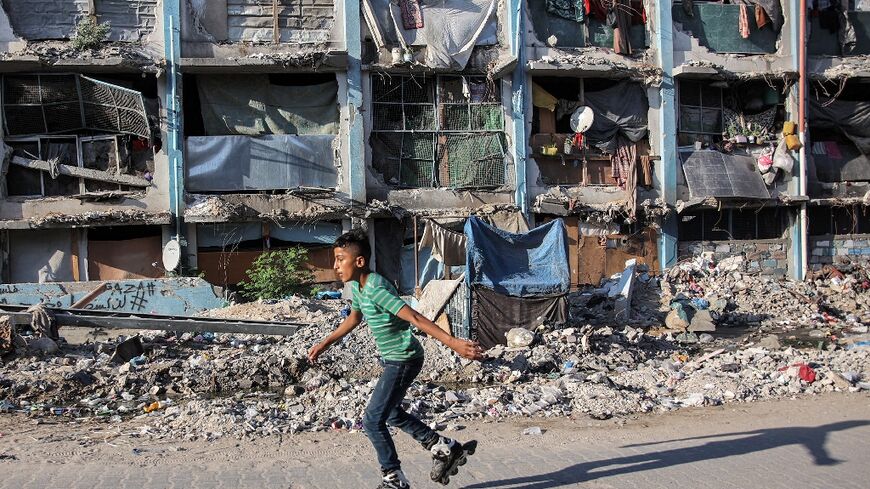 A boy roller-blades past a destroyed building at a camp sheltering people displaced by conflict in Jabalia in the northern Gaza Strip