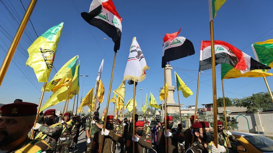 Fighters lift flags of Iraq and paramilitary groups, including al-Nujaba and Kataib Hezbollah, during a funeral in Baghdad for five militants killed a day earlier in a US strike in northern Iraq, on December 4, 2023. 