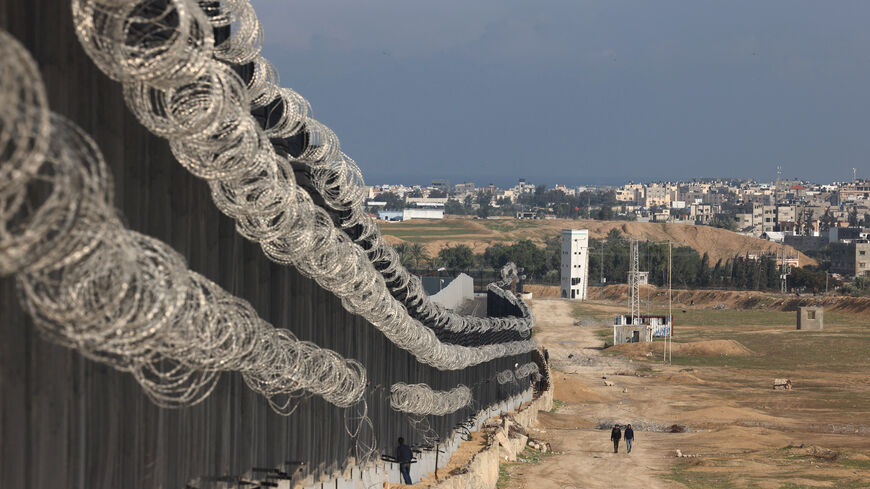 Displaced Palestinians walk next to the border fence between Gaza and Egypt, on February 16, 2024 in Rafah, in the southern Gaza Strip, amid the ongoing conflict between Israel and the Palestinian Hamas militant group. Nearly 1.5 million displaced Palestinians are trapped in Rafah -- more than half of Gaza's populations -- seeking shelter in a sprawling makeshift encampment near the Egyptian border. (Photo by MOHAMMED ABED / AFP) (Photo by MOHAMMED ABED/AFP via Getty Images)