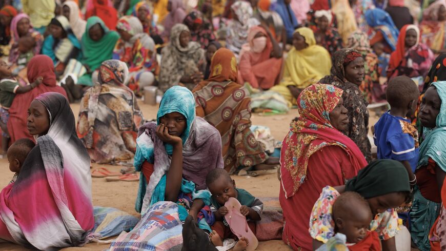 Refugees, mostly women and children, wait for a WFP food distribution point.