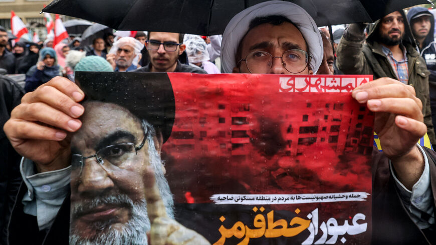 A Shiite Muslim cleric holds a poster reading "crossing a red line" in Persian next to an image of Hassan Nasrallah, the late leader of the Lebanese Hezbollah group, during an anti-Israel protest in Tehran's Palestine Square on Sept. 28, 2024, after Hezbollah confirmed reports of Nasrallah's killing in an Israeli air strike in Beirut the previous day. 