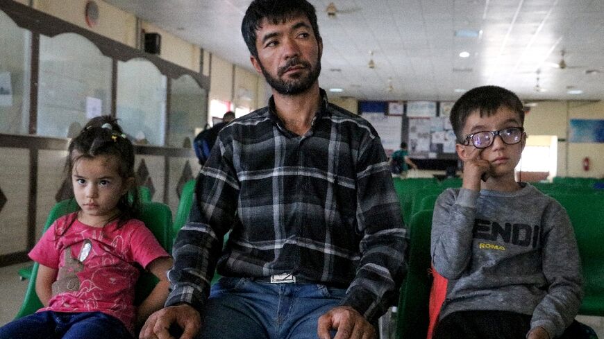 An Afghan refugee sits with his children after their deportation from Iran, at a registration centre near the Afghanistan-Iran border in the Islam Qala district of Herat province