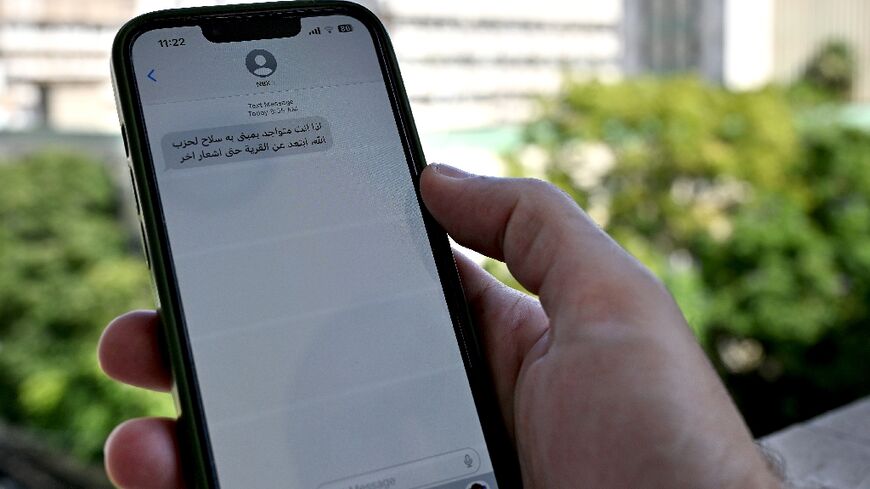 A Lebanese man in Beirut checks a message on his mobile phone calling on people to evacuate areas where Hezbollah operates