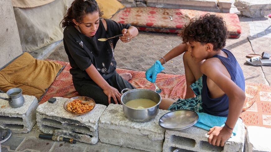 Displaced children eat a cooked meal in their tent at Gaza City's damaged Yarmouk stadium on October 14, 2024