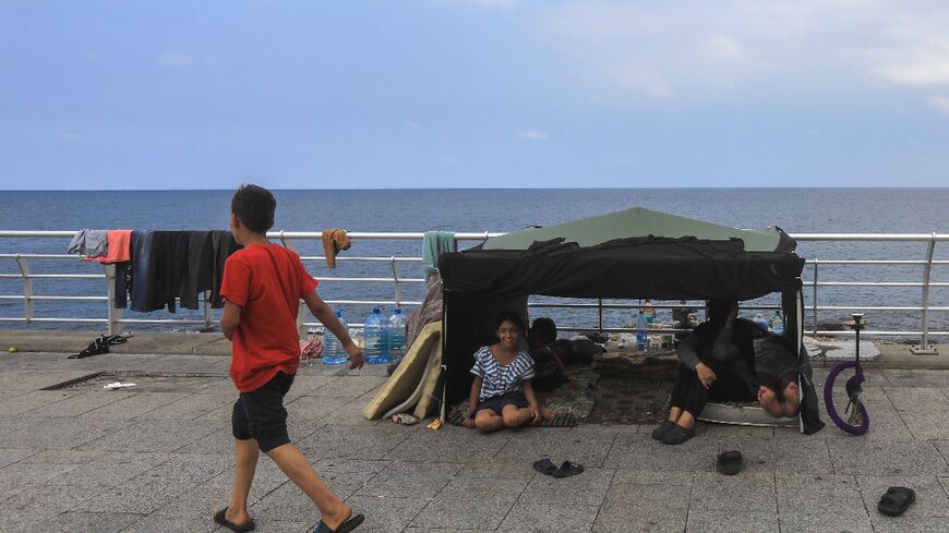 Displaced people sit in a makeshift tent set up on Beirut's seaside promenade