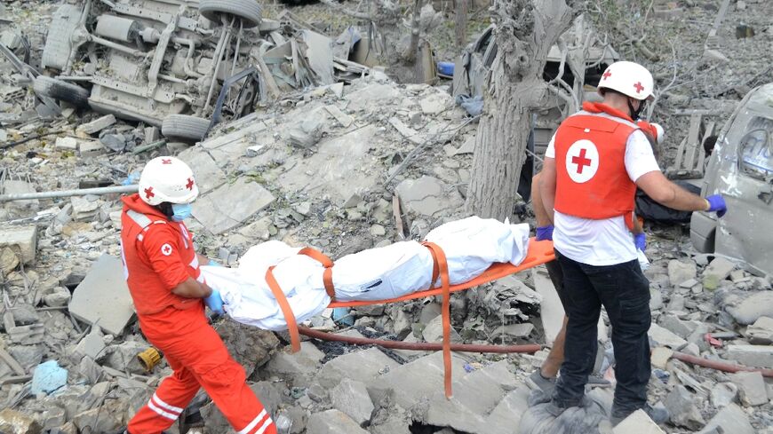 Paramedics carry a body from the rubble at the site of the Israeli airstrike in Aito 