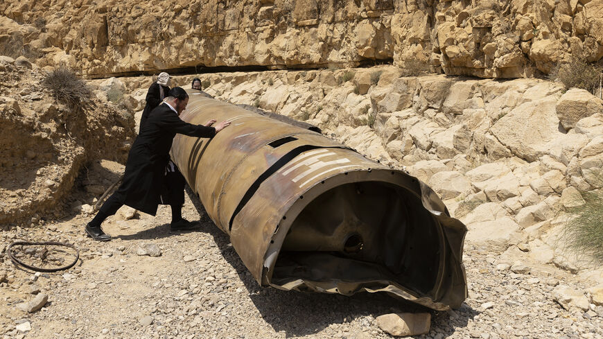 Ultra-Orthodox Jewish men roll a missile debris from Iran's aerial barrage on April 13, located at a channel near the city of Arad, Israel, April 30, 2024.