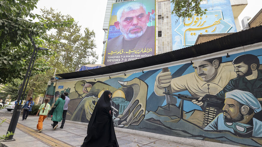 TOPSHOT - People walk past a billboard showing a portrait of newly appointed Hamas leader Yahya Sinwar (top) next to Palestine Square in the Tehran on August 12, 2024. (Photo by ATTA KENARE / AFP) (Photo by ATTA KENARE/AFP via Getty Images)