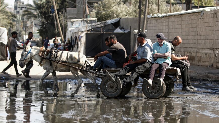 Displaced people ride on a donkey-drawn cart through a muddy puddle in Deir al-Balah in the central Gaza Strip on Sept. 30, 2024.