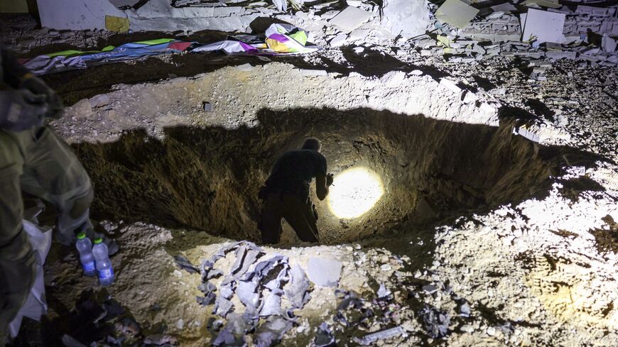 Members of Israel's Home Front Command and police forces inspect a crater left by an exploded projectile at a heavily damaged school building in Israel's southern city of Gedera.