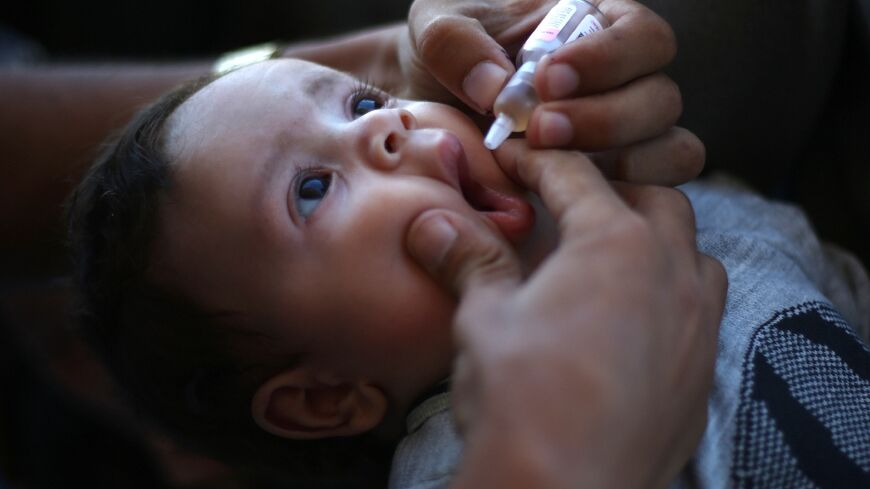 A medic administers a polio vaccine to a Palestinian child in Khan Yunis in the southern Gaza Strip 