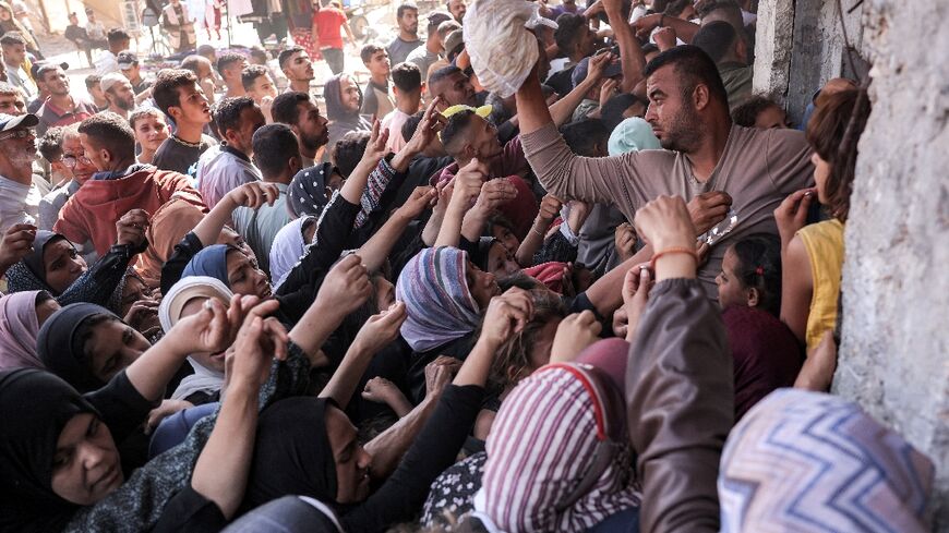 People clamour for bread outside a bakery in the city of Khan Yunis in aid-starved Gaza