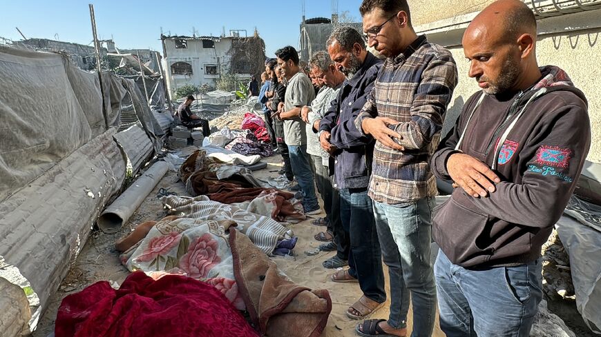 Palestinians pray over bodies of relatives, killed in an overnight Israeli airstrike in Beit Lahia in the northern Gaza Strip