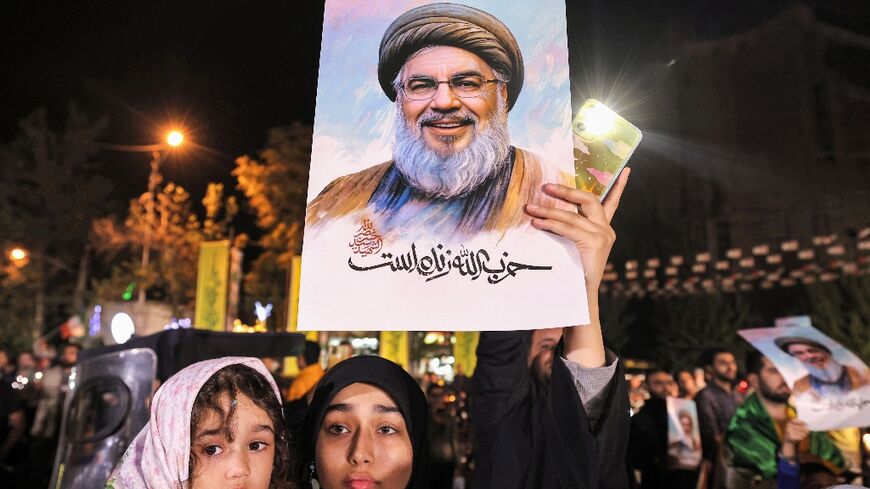 A woman holds a picture of slain Hezbollah leader Hassan Nasrallah at a rally in Tehran after Iran fired a barrage of missiles at Israel