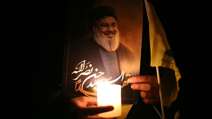 A mourner carries a candle and a portrait of slain Hezbollah chief Hassan Nasrallah during a vigil at the site where he was killed