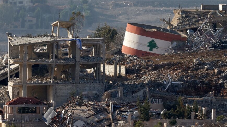 An Israeli flag hangs on a destroyed building while a Lebanese flag is painted on another in the southern Lebanese village of Meiss El-Jabal