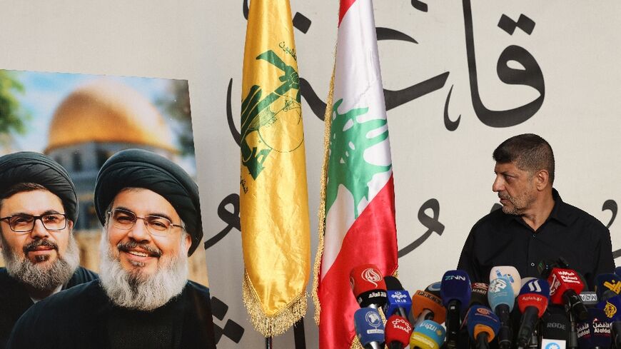 Hezbollah spokesman Mohammad Afif speaks next to portraits of slain militant leaders Hassan Nasrallah and Hashem Safieddine, killed by Israel