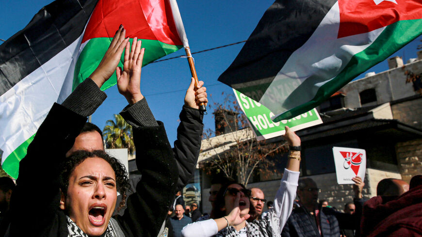 People wave Palestinian and Jordanian flags and chant slogans as they march during a demonstration near the US embassy in the capital Amman in solidarity with the people of Gaza on December 15, 2023, amid the continuing battles between Israel and the militant group Hamas. (Photo by Khalil MAZRAAWI / AFP) (Photo by KHALIL MAZRAAWI/AFP via Getty Images)