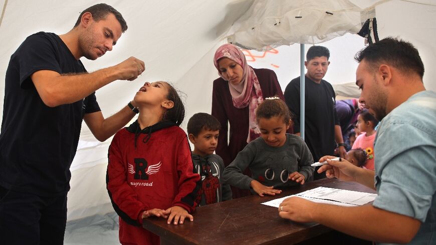 A medic administers polio vaccine to a Palestinian child at Abdel Aziz Rantissi hospital in the Gaza City area of north Gaza -- the campaign resumed after a halt due to Israeli bombing