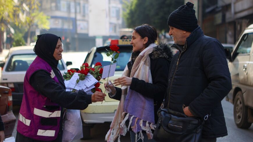 A woman offers a rose to a pedestrian in Aleppo, the first major city taken by rebels on their rapid push that ended with the fall of Bashar al-Assad's government