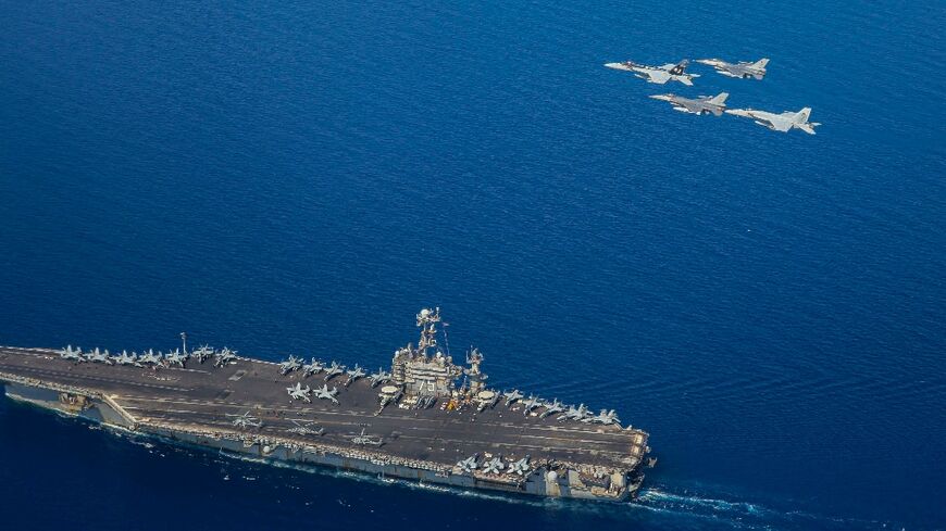 A handout file picture from the US Navy showing the USS Harry S Truman with F/A-18 and F-16 jets flying overhead