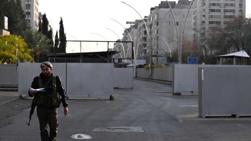 A Syrian rebel fighter stands guard outside the long-feared defence ministry compound in central Damascus from which the Assads' myriad intelligence agencies operated.