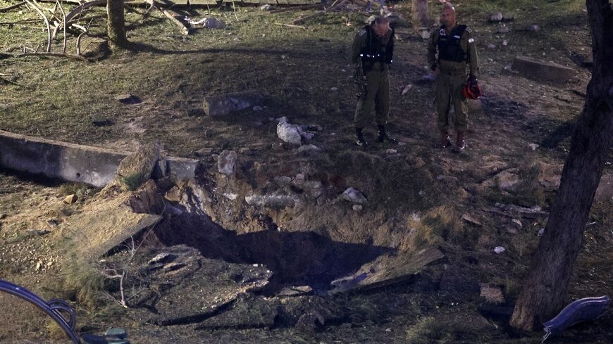 Israeli emergency responders inspect a crater at the site where a projectile fired from Yemen landed in Tel Aviv