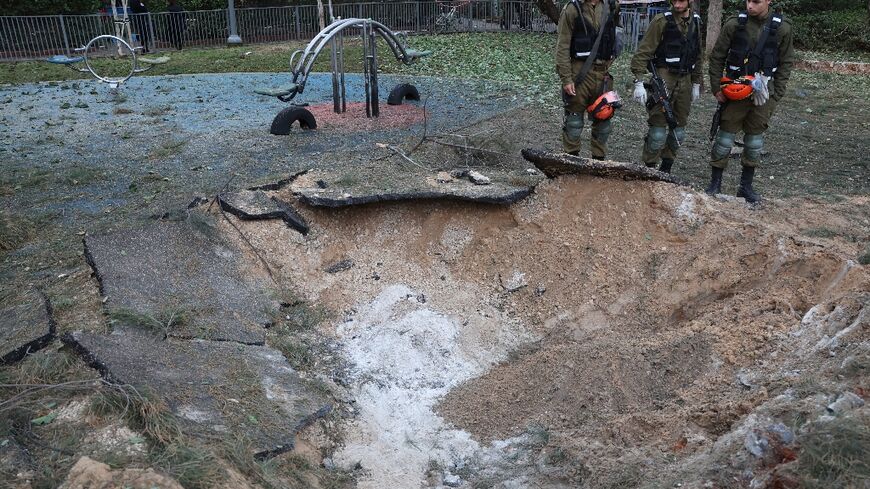 Israeli emergency responders inspect a crater at the site where a projectile fired from Yemen landed in Tel Aviv on December 21, 2024