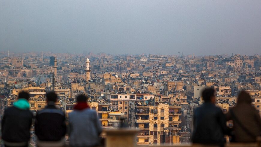 Young Syrians sit together at a spot overlooking the northern Syrian city of Aleppo