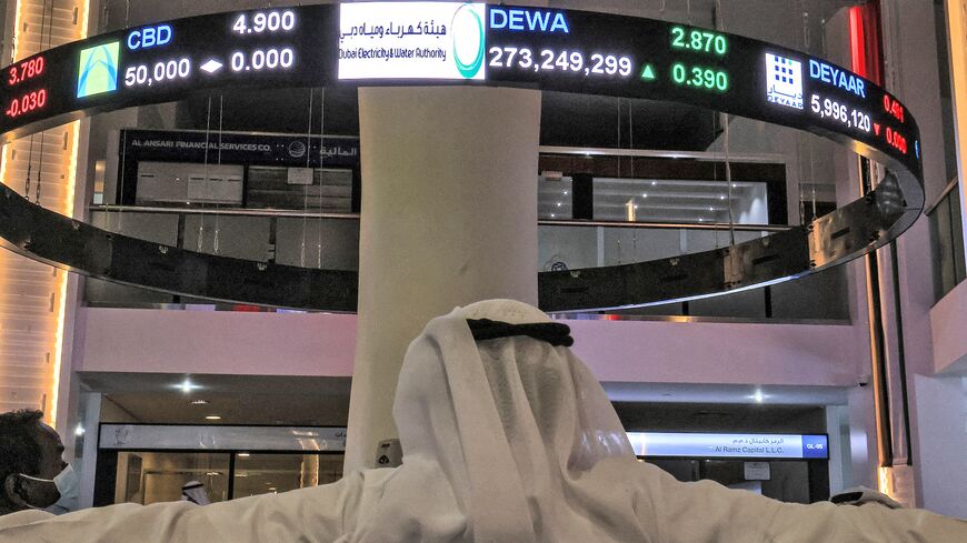 A man watches stock movements on a display at the Dubai Financial Market stock exchange in the Gulf emirate on April 12, 2022.