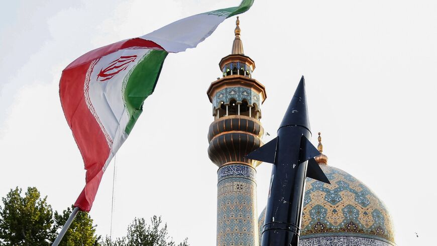 Iranians lift up a flag and the mock up of a missile during a celebration following Iran's missiles and drones attack on Israel, on April 15, 2024, at Palestine square in central Tehran. 