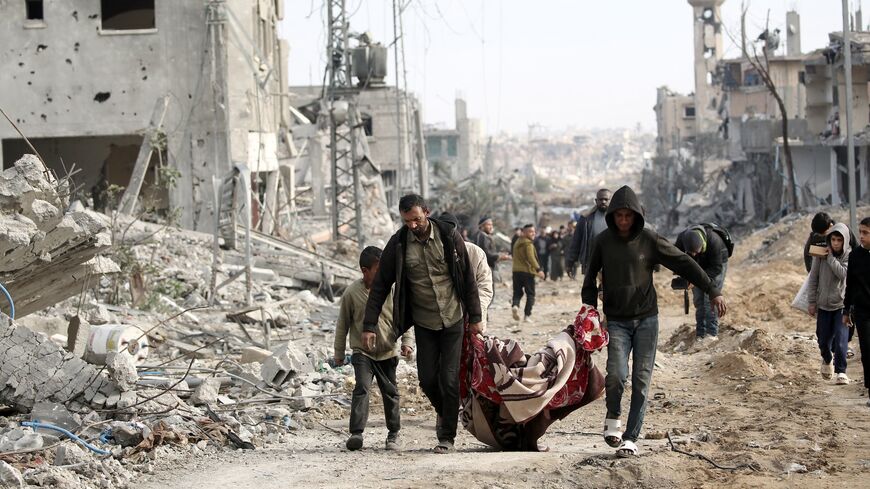 Palestinian men carry a body retrieved from under the rubble following their return to Nuseirat, in the central Gaza Strip, after Israeli shelling of the camp stopped, Nov. 29, 2024.